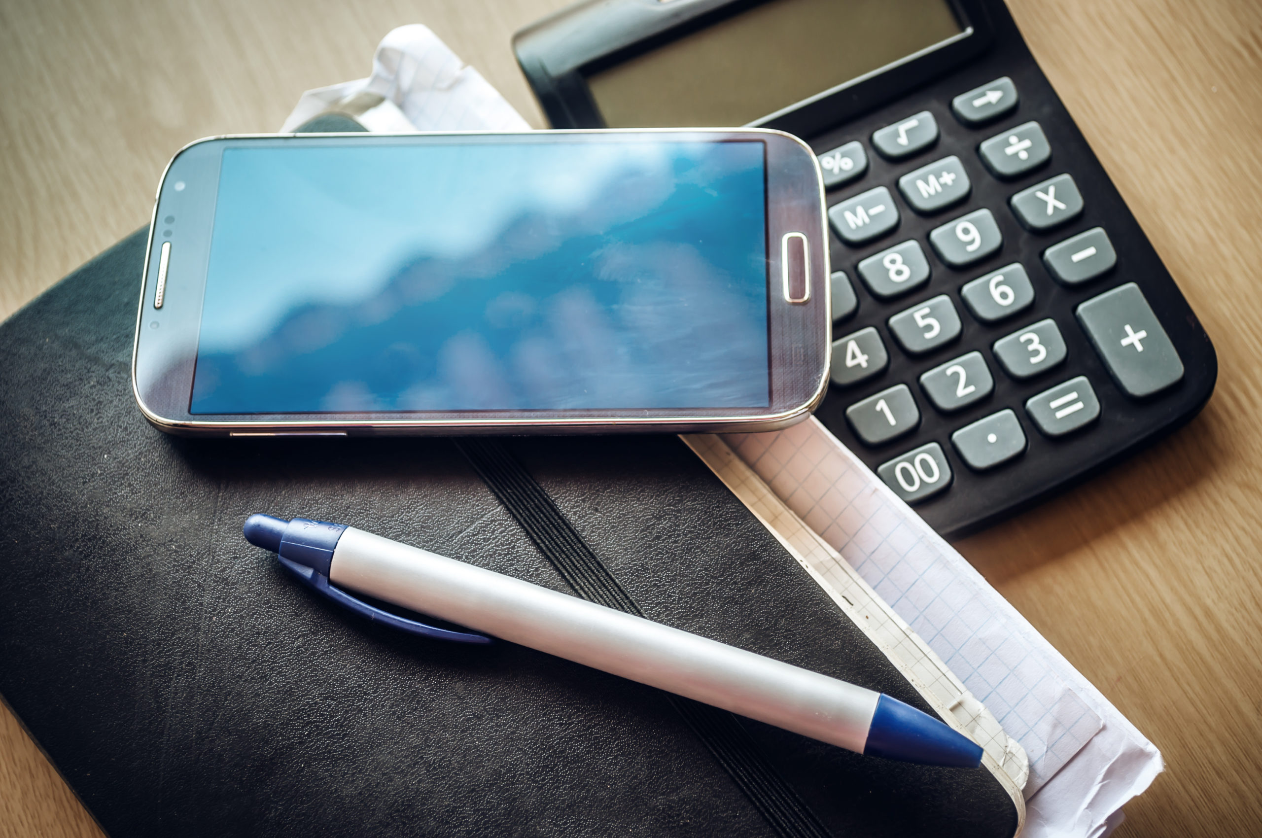 Un agenda papier, une calculatrice un stylo et un téléphone pour symboliser le télésecrétariat